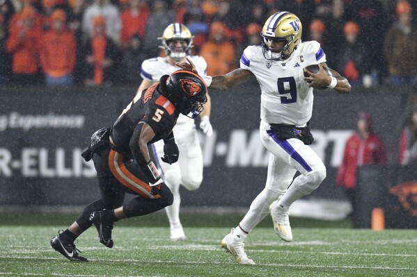 Washington quarterback Michael Penix Jr. (9) dodges Oregon State linebacker Easton Mascarenas-Arnold (5) during the first half of an NCAA college football game Saturday, Nov. 18, 2023, in Corvallis, Ore. (AP Photo/Mark Ylen)
