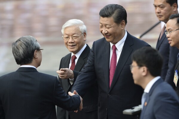 FILE - Chinese President Xi Jinping, center, is introduced by Vietnamese Communist Party General Secretary Nguyen Phu Trong, second left, to Tran Quoc Vuong, politburo member and standing member of the Communist Party Secretariat during a welcoming ceremony at the presidential palace in Hanoi, Vietnam, Sunday, Nov. 12, 2017. Xi will arrive in Vietnam on Tuesday, Dec. 12, 2023, seeking to further deepen ties with its neighbor that is deepening diplomatic relations with Western-aligned countries. In his first visit since 2017. (Hoang Dinh Nam/Pool Photo via AP, File)