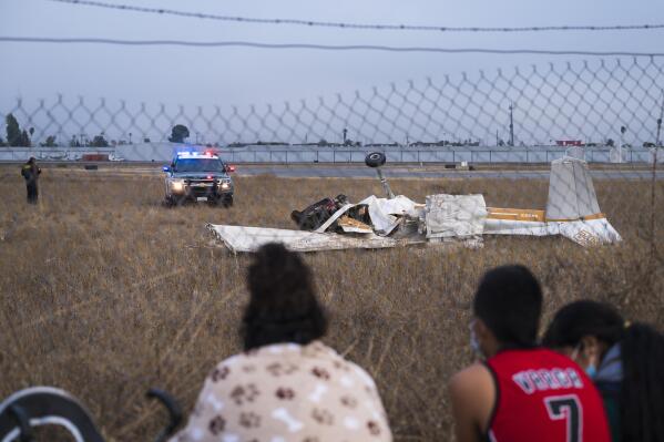 People look at the wreckage from a plane crash at Watsonville Municipal Airport in Watsonville, Calif., Thursday, Aug. 18, 2022. (AP Photo/Nic Coury)
