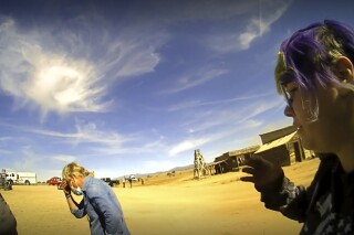 In this screen grab from lapel camera video provided by the Santa Fe County Sheriff's Office, movie set armorer Hannah Gutierrez-Reed, right, speaks with a sheriff's deputy as other colleagues, at center and left, react on the set of the western move "Rust," shortly after the fatal shooting of cinematographer Halyna Hutchins by Alec Baldwin during a rehearsal, Oct. 21, 2021, in New Mexico. The scheduled trial next week of the movie weapons supervisor in the fatal shooting of a cinematographer by Alec Baldwin may hinge on an enduring mystery: How did live ammunition find its way onto the set of a film set where it was expressly prohibited? (Santa Fe County Sheriff's Office via AP)