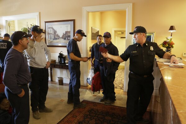 
              Firefighters from Southern California wait to check into their rooms at the Napa River Inn, Monday, Oct. 16, 2017, in Napa, Calif. First responders have been allowed to stay free at the hotel all week. With the winds dying down, fire crews gained ground as they battled wildfires that have devastated California wine country and other parts of the state over the past week, and thousands of people got the all-clear to return home. (AP Photo/Eric Risberg)
            
