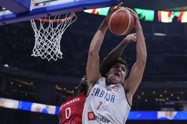 Canada guard Luguentz Dort, left, and Serbia guard Bogdan Bogdanovic battle for a rebound during a Basketball World Cup semi final game in Manila, Philippines, Friday, Sept. 8, 2023. (AP Photo/Michael Conroy)