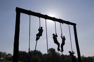 FILE - Freshman midshipmen, known as plebes, climb ropes on an obstacle course during Sea Trials, a day of physical and mental challenges that caps off the freshman year at the U.S. Naval Academy in Annapolis, Md., May 13, 2014. The Navy is adding two weeks to boot camp in a major overhaul aimed at improving recruits' war fighting and emergency skills while also focusing on character issues such as sexual assault, hazing and extremism in the ranks. Navy officials say expanding boot camp to 10 weeks will provide more leadership training and ensure sailors are reporting to their jobs better prepared for duty. (AP Photo/Patrick Semansky, File)