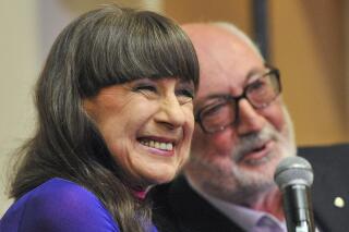 Seekers lead singer Judith Durham with fellow band member and guitarist Athol Guy attends at media conference in Melbourne, Australia on Sept. 10, 2013. Lead singer of The Seekers, Durham, has died aged 79 in Melbourne, Friday, Aug. 5, 2022 after suffering complications from a long-standing lung disease, her management said. (Julian Smith/AAP Image via AP)