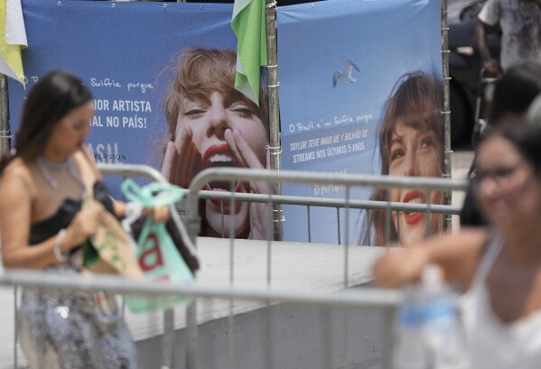 Taylor Swift fans wait for the doors of Nilton Santos Olympic stadium to open for her Eras Tour concert amid a heat wave in Rio de Janeiro, Brazil, Saturday, Nov. 18, 2023. A 23-year-old Taylor Swift fan died at the singer's Eras Tour concert in Rio de Janeiro Friday night, according to a statement from the show's organizers in Brazil. (AP Photo/Silvia Izquierdo)