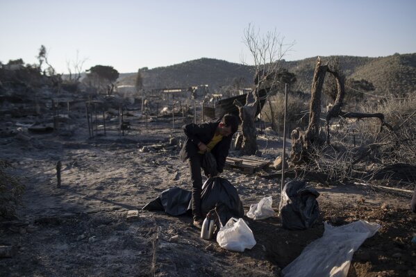 A migrant is tighten a plastic bag in the burned Moria refugee camp on the northeastern island of Lesbos, Greece, Thursday, Sept. 10, 2020. A second fire in Greece's notoriously overcrowded Moria refugee camp destroyed nearly everything that had been spared in the original blaze, Greece's migration ministry said Thursday, leaving thousands more people in need of emergency housing. (AP Photo/Petros Giannakouris)