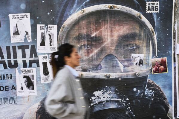An advertisement for Netflix series "The Eternaut" is partially covered by posters of sci-fi comic author Hector Oesterheld and his daughters, who were forcibly disappeared during Argentina's military dictatorship (1976–1983), in Buenos Aires, Argentina, Tuesday, May 6, 2025. (AP Photo/Rodrigo Abd)