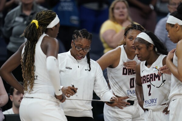 Atlanta Dream head coach Tanisha Wright, center, draws on a whiteboard during overtime of a WNBA basketball game against the Minnesota Lynx, Friday, Sept. 1, 2023, in Minneapolis. (AP Photo/Abbie Parr)