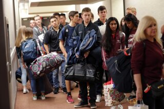 
              Student survivors from Marjory Stoneman Douglas High School, scene of a deadly mass shooting last Wednesday, prepare to load their bags on busses, after spending the night in the civic center in Tallahassee, Fla., Wednesday, Feb. 21, 2018. Several busloads of survivors marched from the civic center to the state capitol to pressure lawmakers on gun control reform. (AP Photo/Gerald Herbert)
            