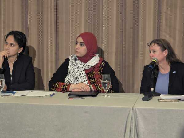 Mapheze Saleh, center, wife of arrested and detained Georgetown University scholar Badar Khan Suri, listens during a press conference about her husband's release following his hearing at Federal District Court for the Eastern District of Virginia, in Alexandria, Va., Thursday, May 14, 2025 (AP Photo/Nathan Ellgren)