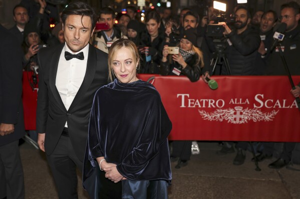 CORRECTS YEAR TO 2022- Italian Premier Giorgia Meloni, center, and her partner Andrea Giambruno arrive for theseason opener at the Scala Opera house, in Milan, northern Italy, Dec. 7, 2022. Meloni announced Friday, Oct. 20, 2023 that she is separating from her partner and the father of her young daughter after nearly a decade together. In a statement posted on social media, Meloni said her relationship with Andrea Giambruno had ended. She said their paths had diverged “for some time.” The announcement came after Giambruno, an on-air television personality, was caught on audio seemingly making lewd remarks to colleagues. (Alessandro Bremec/LaPresse via AP)