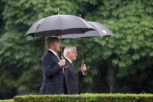 German President Frank-Walter Steinmeier, right, and Dutch King Willem-Alexander, left, attend a military welcome ceremony as part of a meeting in Berlin, Germany, Monday, July 5, 2021. The Royals arrived in Germany for a three-day visit that was delayed from last year because of the coronavirus pandemic.  (AP Photo/Michael Sohn)