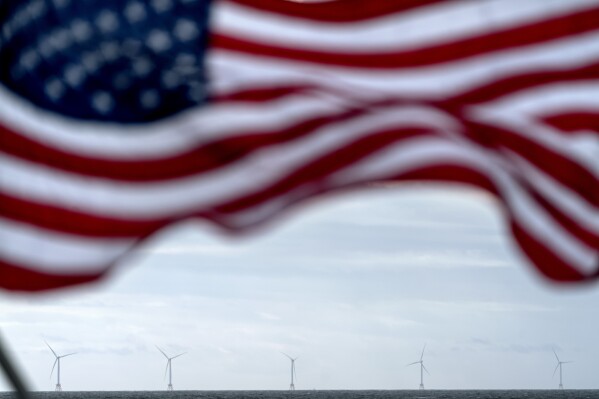 FILE - The five turbines of America's first offshore wind farm, owned by the Danish company, Orsted, are seen from a tour boat flying the American flag off the coast of Block Island, R.I., Oct. 17, 2022. The cancellation of two large offshore wind projects in New Jersey is the latest in a series of setbacks for the nascent U.S. offshore wind industry, jeopardizing President Joe Biden's goal of powering 10 million homes by towering ocean-based turbines by the end of the decade. (AP Photo/David Goldman, File)