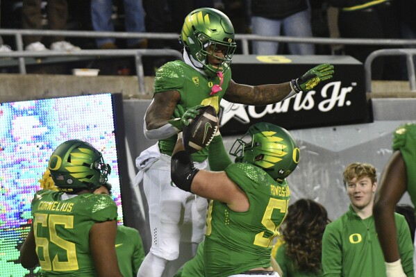 Oregon running back Bucky Irving, top, is hoisted by Oregon offensive lineman Jackson Powers-Johnson (58) after a touchdown during the first half of an NCAA college football game against Oregon State, Friday, Nov. 24, 2023, in Eugene, Ore. (AP Photo/Mark Ylen)