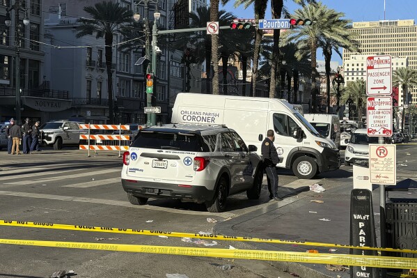 A coroner's van is parked on the corner of Bourbon St. and Canal St, after a vehicle raced into a crowd of revelers early on New Year's Day, in New Orleans on Wednesday, Jan. 1, 2025. (AP Photo/Jack Brook)