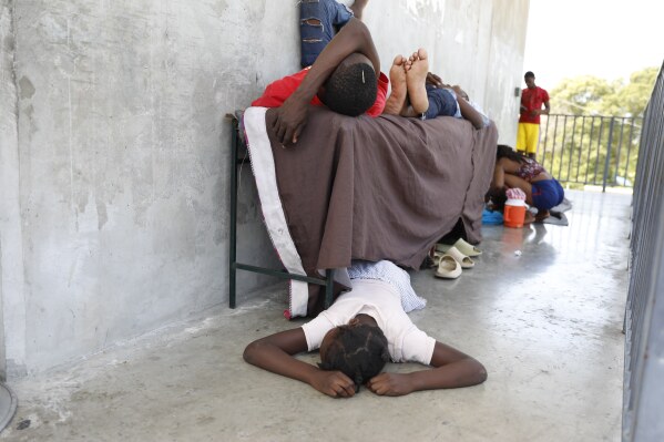 Residents who were displaced from their homes due to clashes between police and gang members, rest at a public school serving as a shelter in Port-au-Prince, Haiti, Friday, March 8, 2024. (AP Photo/Odelyn Joseph)