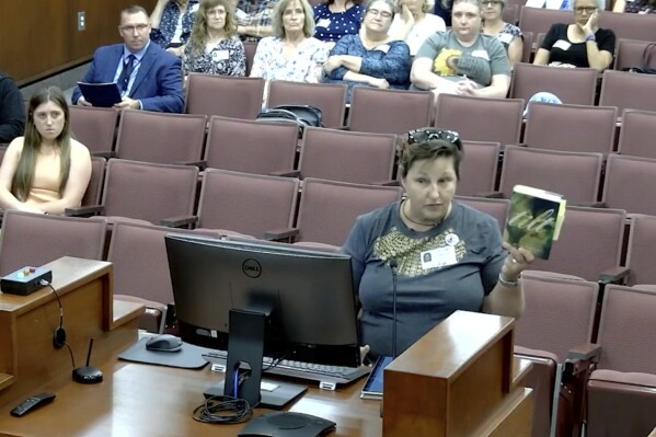 In this image from video posted by the Forsyth County school board, T.J. McKinney, a departing teacher of autistic students at a Forsyth middle school, speaks during a meeting of the board in Cumming, Ga., on June 20, 2023. She said students need to see their own struggles reflected in books, and it's pointless to shield older students from vulgarity or sex. “The book is not introducing kids to sex. If you’re in high school, they’re having sex," McKinney said. “These kids are saying it. They’re doing it. They are not learning this from books." (Forsyth County Schools via AP)