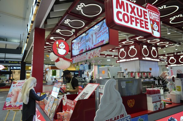 Customer service assistant Saleha Baharuddin, left, buys drink from Mixue after her work at a shopping outlet in Sepang, Malaysia, Tuesday, Feb. 25, 2025. (AP Photo/Vincent Thian)