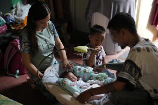 Hyancinth Charm Garing, left, and husband Jeremy, right, play with their month-old daughter inside their home at a new community for victims of super Typhoon Haiyan in Tacloban, central Philippines on Sunday Oct. 23, 2022. Garing and his family settled at a relocation site three years ago after their village was wiped out when the super typhoon struck in 2013, killing six family members and his year-old daughter. (AP Photo/Aaron Favila)