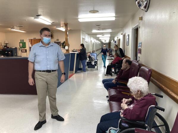 Tim Corbin, left, the administrator of Truman Lake Manor, passes through the hallway of the nursing home on Feb. 14, 2023, in Lowry, Mo. The facility was cited in December for a violation of the federal vaccination requirement for health care workers but subsequently came into compliance. Corbin believes it's time for the vaccination mandate to end. (AP Photo/David A. Lieb)