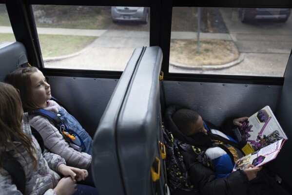 Natalia Bednar, left, rides an electric school bus with classmates, Friday, Feb. 2, 2024, in Chevy Chase, Md. (AP Photo/Tom Brenner)
