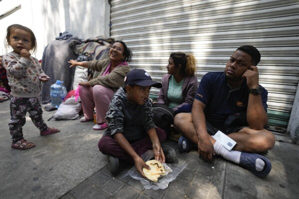 Una familia de inmigrantes venezolanos desayuna junto a las vías del tren en la Ciudad de México, el martes 26 de marzo de 2024. (AP Foto/Fernando Llano)