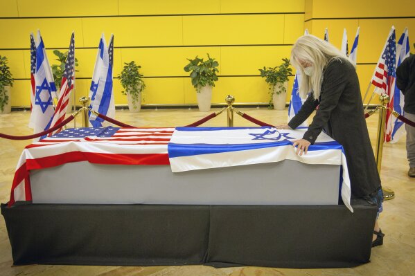 Miriam Adelson touches the casket of her husband, Sheldon Adelson upon arrival to Ben Gurion Airport, near the city of Lod, Israel, Thursday, Jan. 14, 2021. Adelson, the billionaire mogul and power broker who built a casino empire spanning from Las Vegas to China and became a singular force in domestic and international politics has died after a long illness, his wife said Tuesday, Jan. 12, 2021. (Ami Shooman, Israel Hayom/ Pool Photo via AP)