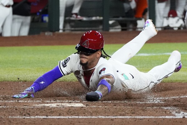 Arizona Diamondbacks' Ketel Marte scores against the Colorado Rockies during the third inning of a baseball game Thursday, March 28, 2024, in Phoenix. (AP Photo/Ross D. Franklin)