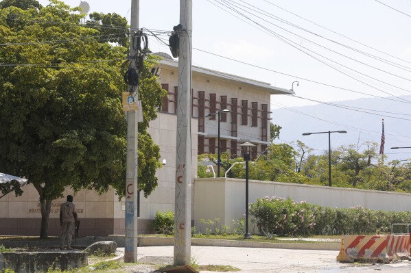 A police officer guards the entrance of the U.S. embassy in Port-au-Prince, Haiti, Sunday, March 10, 2024. The U.S. military said Sunday that it had flown in forces to enhance security at the delegation and allow nonessential personnel to leave. (AP Photo/Odelyn Joseph)