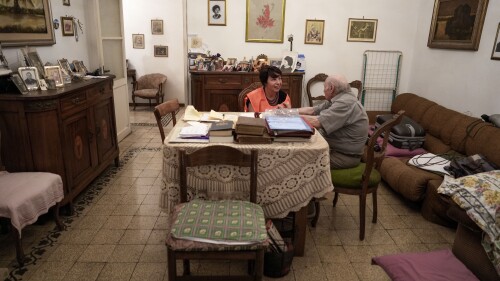 Sant'Egidio Catholic group volunteer Michela Tassani, left, chats with 98-year-old Armando Frajegari in his home, in Rome, Wednesday, July 19, 2023. As an intense heat wave with temperatures close to 40 degrees Celsius in many Italian cities is forcing elderly and fragile people to stay in their homes, Sant'Egidio volunteers check up on them providing company and helping in daily routines such as food shopping. (AP Photo/Andrew Medichini)