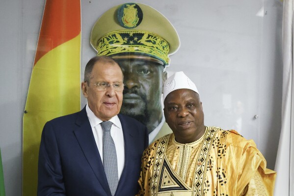2024年6月3日（星期一），俄罗斯外交部新闻社发布的这张照片中，俄罗斯外交部长谢尔盖·拉夫罗夫（左）和几内亚外交部长莫里萨达·库亚特（Morissanda Kouyate）在几内亚科纳克里会晤时，在几内亚总统马马迪·杜姆博亚（Mamadi Doumbouya）的肖像附近合影。俄罗斯外交部长谢尔盖·拉夫罗夫（Sergey Lavrov）周一抵达几内亚，开始他最近一次对西非的访问。西非政变以及对法国和美国等传统盟友日益增长的不满，促成了一些国家转向莫斯科。（俄罗斯外交部新闻社通过美联社）