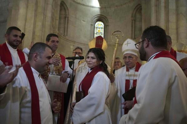 Sally Ibrahim Azar, center, a Palestinian Christian and Council member of the Lutheran World Federation is applauded by clergy after she was ordained as the first female pastor in the Holy Land, in the Old City of Jerusalem, Sunday, Jan. 22, 2023. (AP Photo/Maya Alleruzzo)