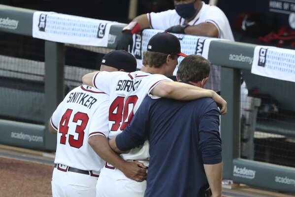 Atlanta Braves manager Brian Snitker and a trainer help pitcher Mike Soroka off the field with an apparent injury, during the third inning of the team's baseball game against the New York Mets, Monday, Aug. 3, 2020, in Atlanta. (Curtis Compton/Atlanta Journal-Constitution via AP)