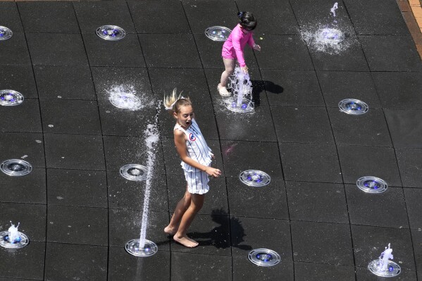Kids cool off at Gallagher Way park fountain during hot weather in Chicago, Sunday, June 16, 2024. (AP Photo/Nam Y. Huh)