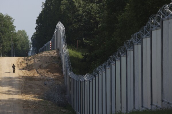 FILE - A Polish border guard patrols the area of a built metal wall on the border between Poland and Belarus, near Kuznice, Poland, on June 30, 2022. NATO allies located along the alliance’s eastern front are growing increasingly worried about the presence of Russia-linked Wagner group mercenaries in Belarus. (AP Photo/Michal Dyjuk, File)