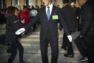 
              In this Tuesday, March 5, 2019 photo, a security official tries to keep journalists back from the steps of the Great Hall of the People as delegates arrive for the opening session of China's National People's Congress (NPC) in Beijing. The annual meeting of China's legislature is a highly scripted affair, but quirky moments and offbeat details lurk around the edges and behind the scenes. (AP Photo/Mark Schiefelbein)
            
