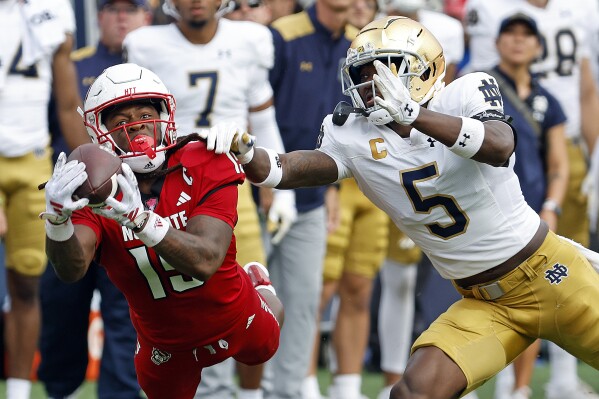 North Carolina State's Keyon Lesane (15) hauls in a pass as Notre Dame's Cam Hart (5) defends during the second half of an NCAA college football game in Raleigh, N.C., Saturday, Sept. 9, 2023. (AP Photo/Karl B DeBlaker)