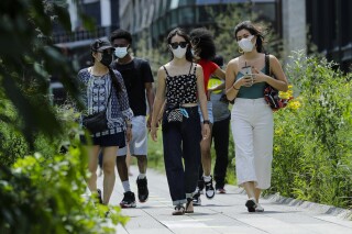 People wearing protective masks during the coronavirus pandemic walk along the High Line Park, Thursday, July 16, 2020, in New York. Some on social media have falsely claimed that Transportation Security Administration managers were told that mask mandates and other pandemic-era restrictions will start returning this fall. The TSA and the Centers of Disease Control and Prevention confirmed that the rumors are not true.(AP Photo/Frank Franklin II)