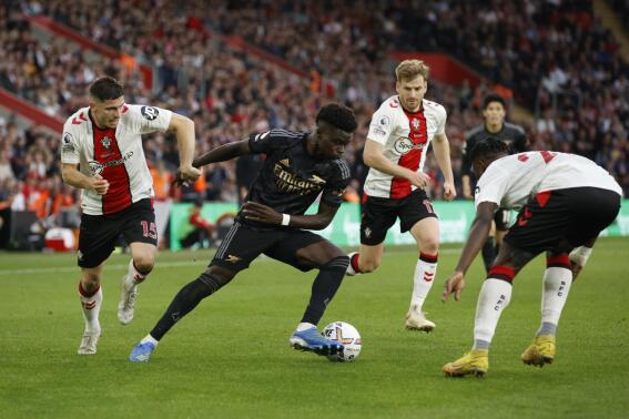 Arsenal's Bukayo Saka, second left, fights for the ball with Southampton's Romain Perraud, left, and Mohammed Salisu, right, during the English Premier League soccer match between Southampton and Arsenal at the Saint Mary's Stadium in Southampton, Sunday, Oct. 23, 2022. (AP Photo/David Cliff)