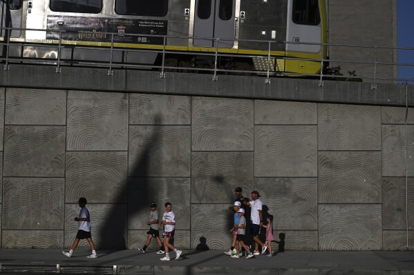 A group of pedestrians walk across the street from the downtown Metropolitan Detention Center Tuesday, June 17, 2025, in Los Angeles. (AP Photo/Wally Skalij)