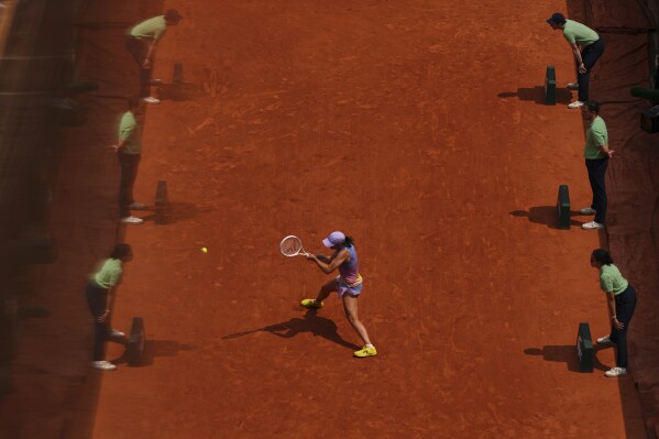 Referees are reflected in a glass as Poland's Iga Swiatek plays a shot against Ukraine's Elina Svitolina during their quarterfinal match of the French Tennis Open at the Roland-Garros stadium in Paris, Tuesday, June 3, 2025. (AP Photo/Aurelien Morissard)