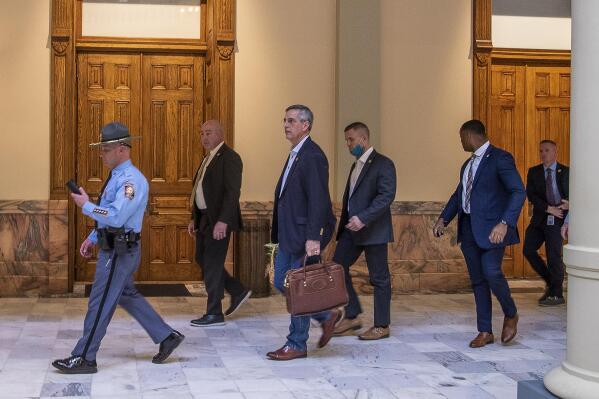 FILE - Lead by a Georgia State Trooper, Georgia Secretary of State Brad Raffensperger, center, exits the Georgia State Capitol building after hearing reports of threats, Wednesday, Jan. 6, 2021, in Atlanta. During the tumultuous period immediately following the November 2020 presidential election, election workers across the country faced harassment and threats. Since then, legislators in a small but growing number of states have proposed measures to help protect those workers by creating or boosting penalties for such threats or assaults. (Alyssa Pointer/Atlanta Journal-Constitution via AP, File)