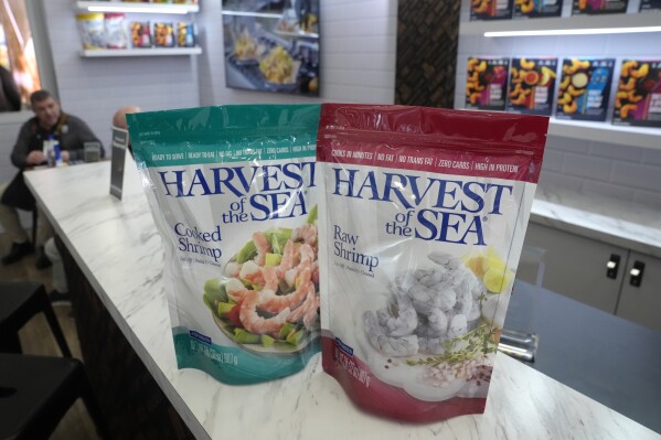 Harvest of the Sea shrimp packets are displayed on a counter at a Harvest of the Sea exhibit booth at the North American Seafood Expo, Monday, March 11, 2024, in Boston. Shrimp pulled from ponds alongside a busy highway in India were loaded into Wellcome KingWhite branded trucks. In the past year, Wellcome KingWhite has exported shrimp to several U.S. companies including Harvest of the Sea. (AP Photo/Steven Senne)