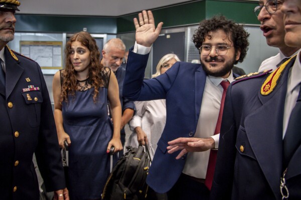 Patrick Zaki waves upon his arrival at the Milan Malpensa airport, Italy, Sunday, July 23, 2023. Egypt on Thursday released two human rights defenders, including one who has ties with Italy, their lawyers said, concluding two cases that drew significant international criticism and attention. The releases of Patrick George Zaki, an activist and postgraduate student in Italy, and Mohamed el-Baker, a human rights lawyer, came a day after they were pardoned by Egyptian President Abdel Fattah el-Sissi along with four other people. (Claudio Furlan/LaPresse via AP)