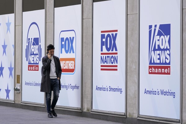 FILE - A person walks past the News Corp. and Fox News headquarters on April 19, 2023, in New York. New York City's pension funds and the state of Oregon sued Fox Corporation on Tuesday, Sept. 12, alleging the company harmed investors by allowing Fox News to broadcast falsehoods about the 2020 election that exposed the network to defamation lawsuits. (AP Photo/Mary Altaffer, File)