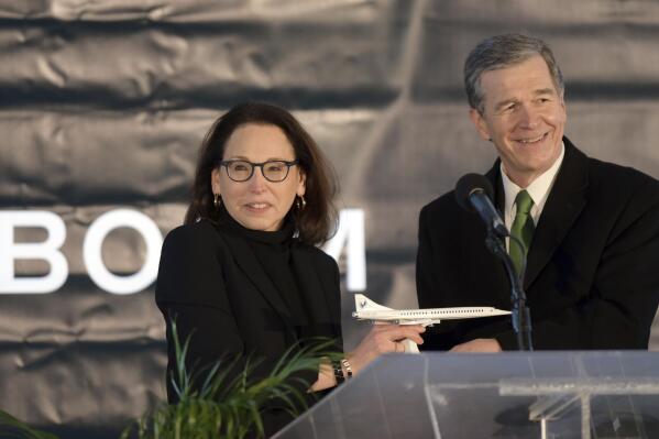 North Carolina Gov. Roy Cooper receives a model of Boom Supersonic's Overture jet from Boom's President and Chief Business Officer Kathy Savitt during an announcement, Wednesday, Jan. 26, 2022 that the aviation company will build its supersonic jet at Piedmont Triad International Airport in Greensboro, N.C. The company said it will employ more than 1700 people by the end of the decade. (Walt Unks/Winston-Salem Journal via AP)