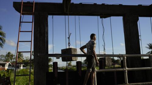 Gate operator Hakim Altaf checks the gate on the seawall in Georgetown, Guyana, Thursday, April 13, 2023. The seawall relies on dozens of workers like Altaf, who set alarms night and day to manually open and close sluice gates known as “kokers” that prevent the Atlantic Ocean from flooding Guyana. (AP Photo/Matias Delacroix)