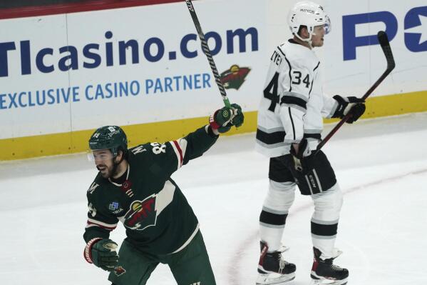 Minnesota Wild's Frederick Gaudreau, left, skates past Los Angeles Kings' Arthur Kaliyev (34) as Gaudreau celebrates a goal by Jacob Middleton during the first period of an NHL hockey game Saturday, Oct. 15, 2022, in St. Paul, Minn. (AP Photo/Jim Mone)