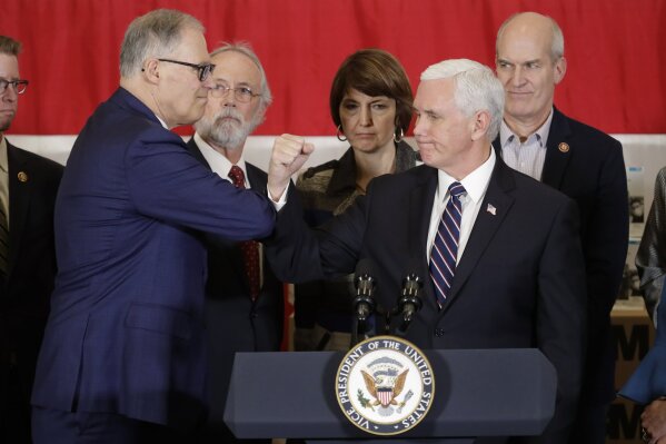 Vice President Mike Pence bumps elbows with Washington Gov. Jay Inslee, left, during a news conference, Thursday, March 5, 2020, at Camp Murray in Washington state. Pence was in Washington to discuss the state's efforts to fight the spread of the COVID-19 coronavirus, and officials have been avoiding shaking hands to prevent the spread of germs. (AP Photo/Ted S. Warren)