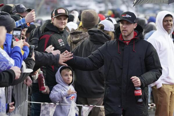 Denny Hamlin, righ, greets fans before the NASCAR Cup Series auto race at Martinsville Speedway on Saturday, April 9, 2022, in Martinsville, Va. (AP Photo/Steve Helber)